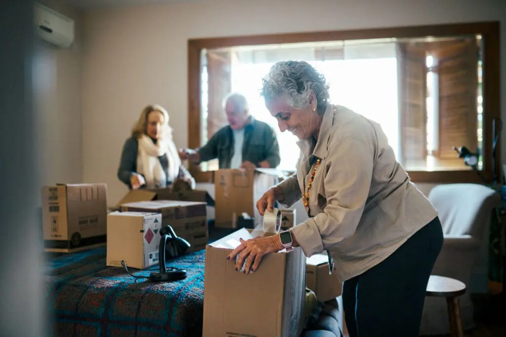 Group of senior friends unpacking boxes in the bedroom as they prepare to downsize for retirement at The Clarendale West End.