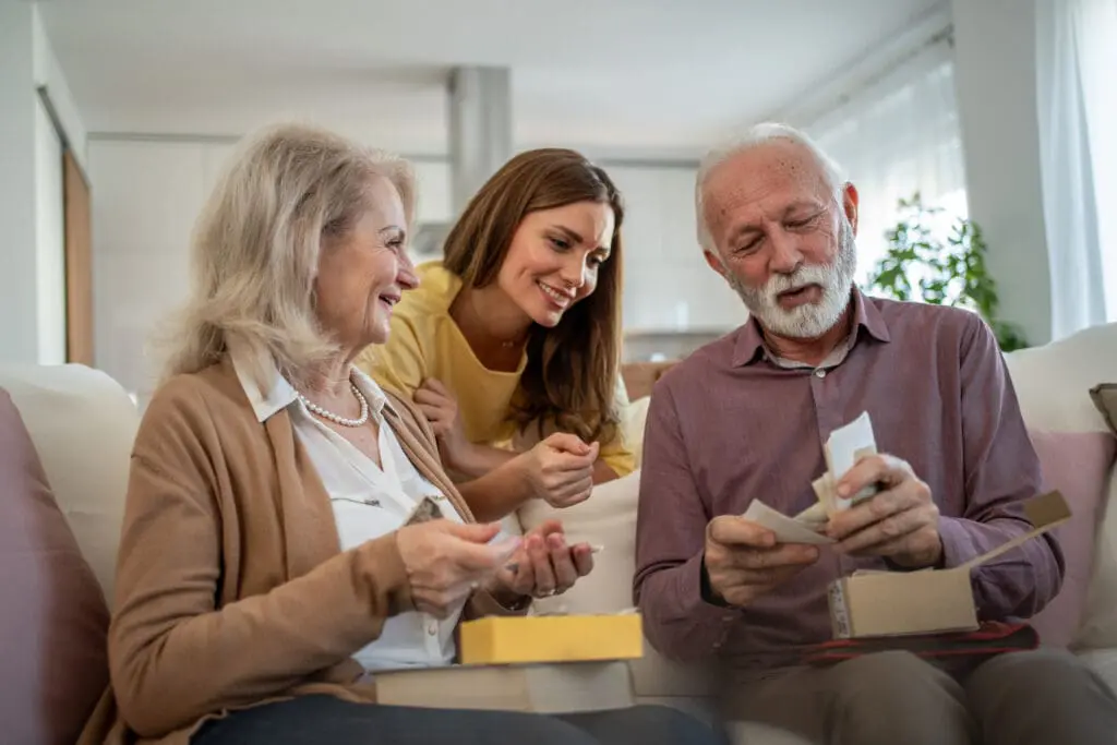 Senior man with Parkinson's disease opening a gift next to wife and daughter at the Clarendale West End.
