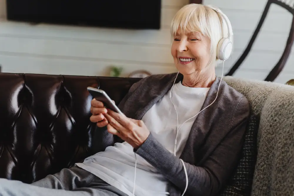 a senior woman sitting in her living room listening to a podcast